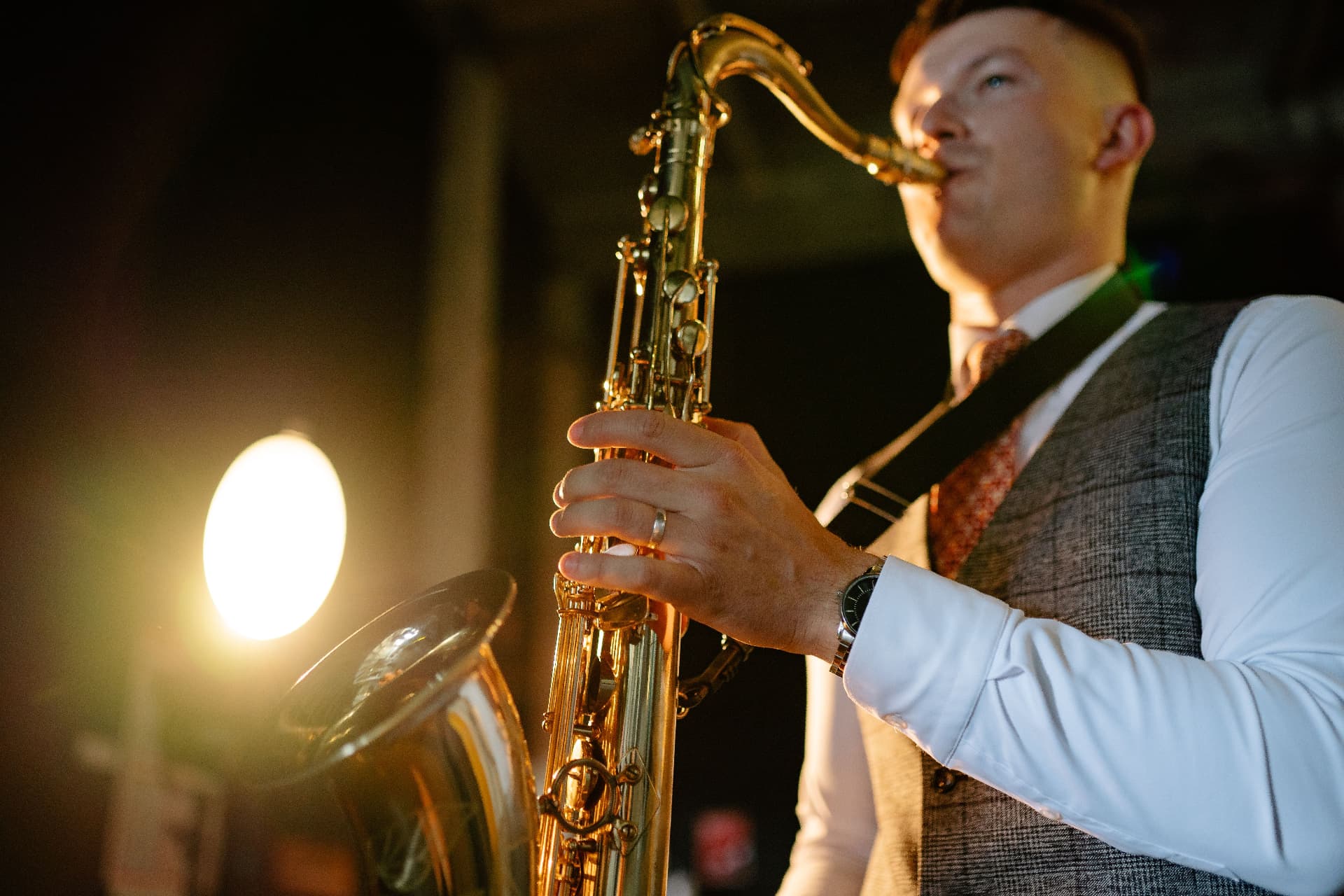 Saxofonista hrající na svatební oslavě ve večerním osvětlení