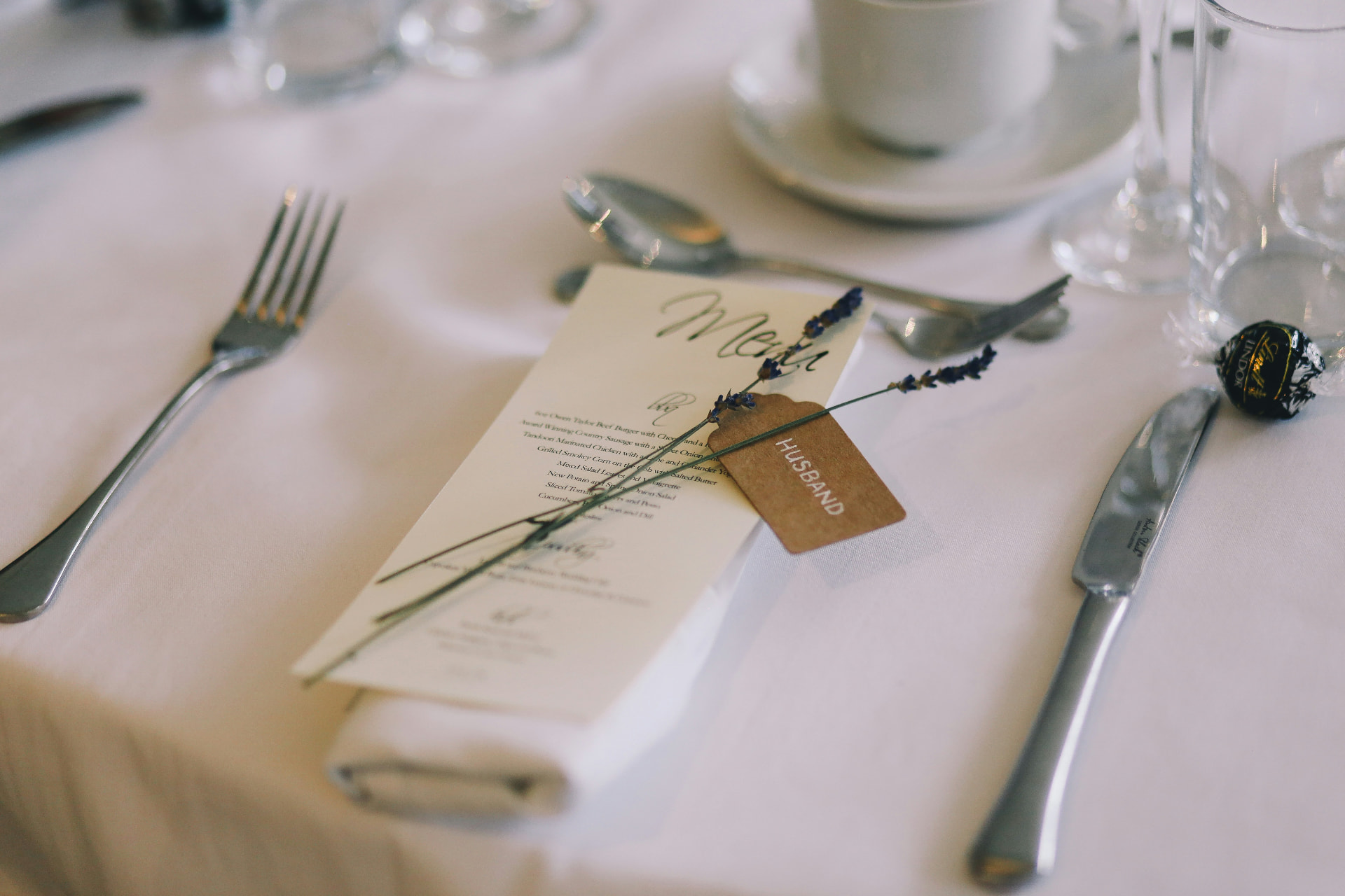 Svatební menu a jmenovka s levandulí na bíle prostřeném stole